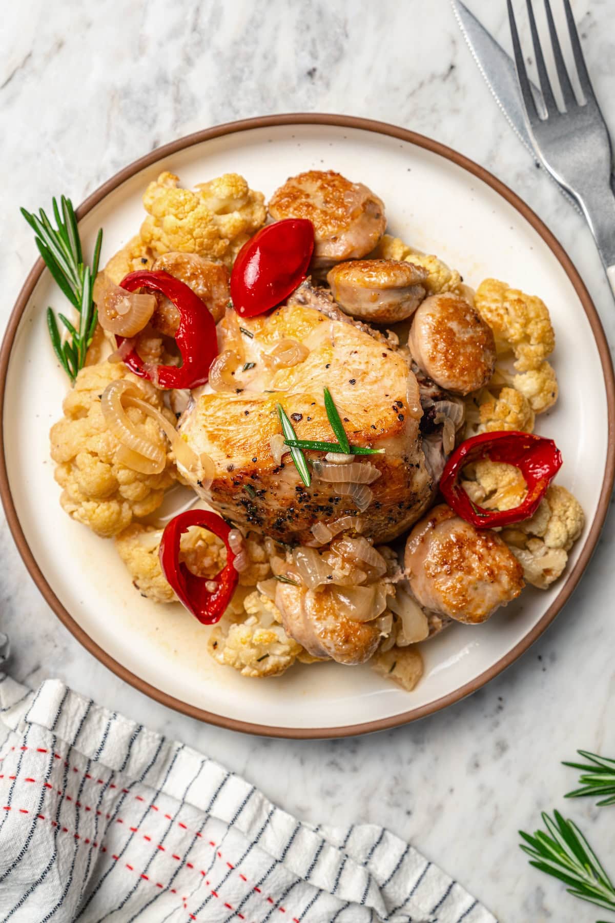 Plate of chicken scarpariello with sausage, peppers, and cauliflower.