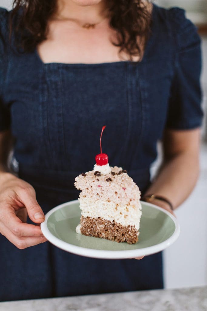 a slice of the no bake neapolitan birthday cake on a green plate held by Joy the Baker