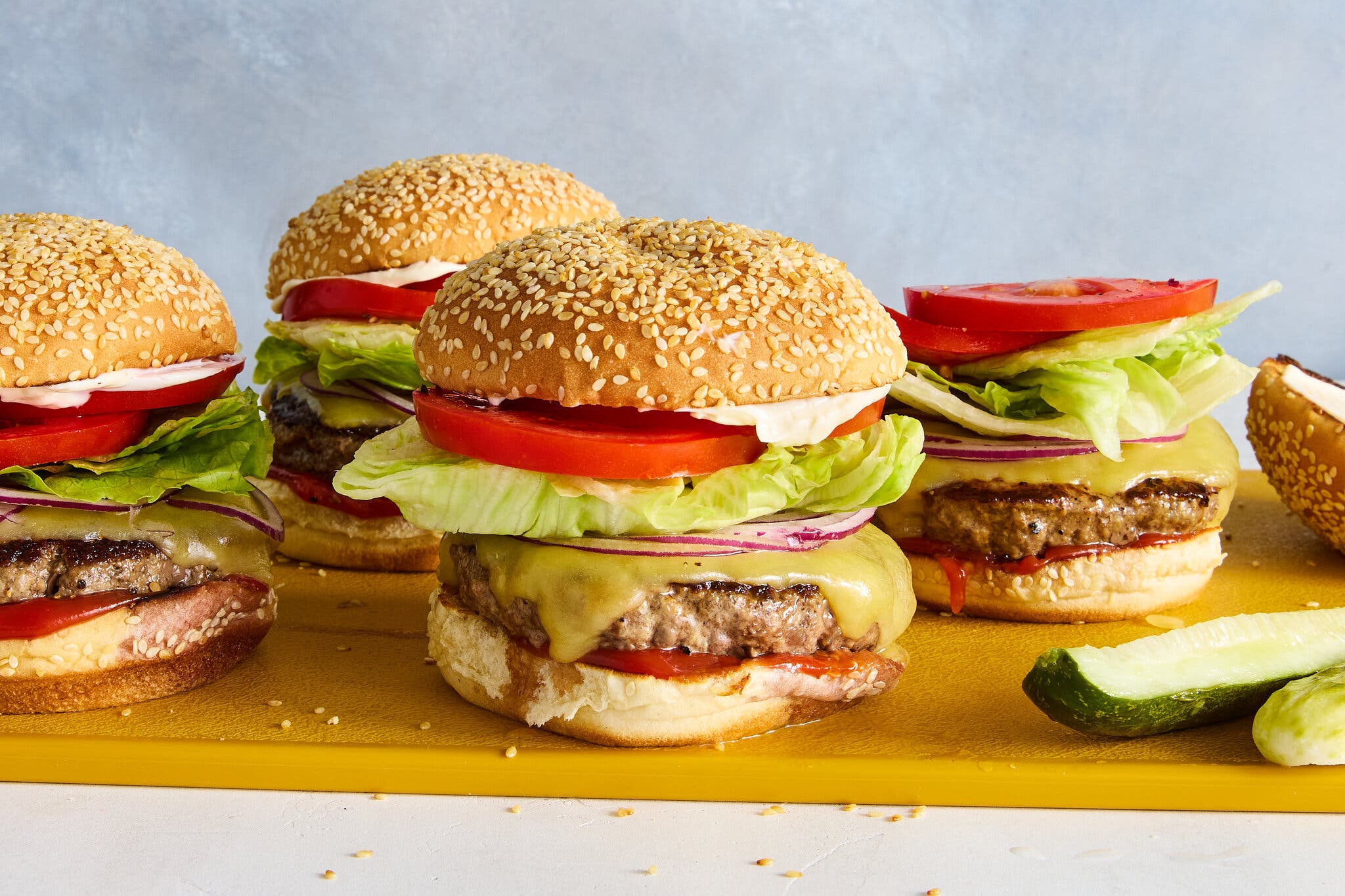 A side image of four burgers on a cutting board.