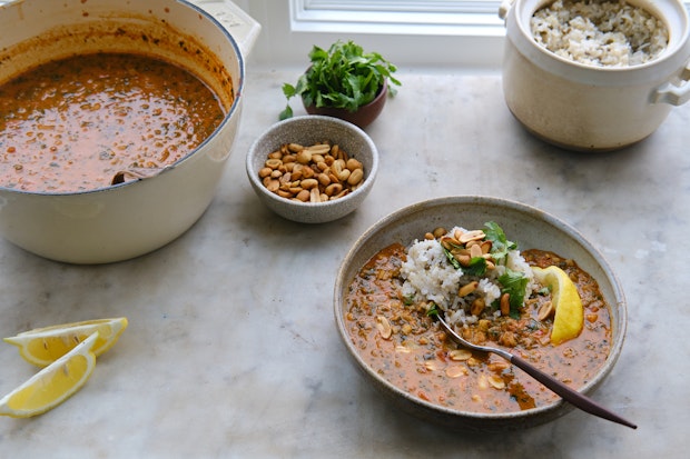 Pot of peanut soup being served on marble table
