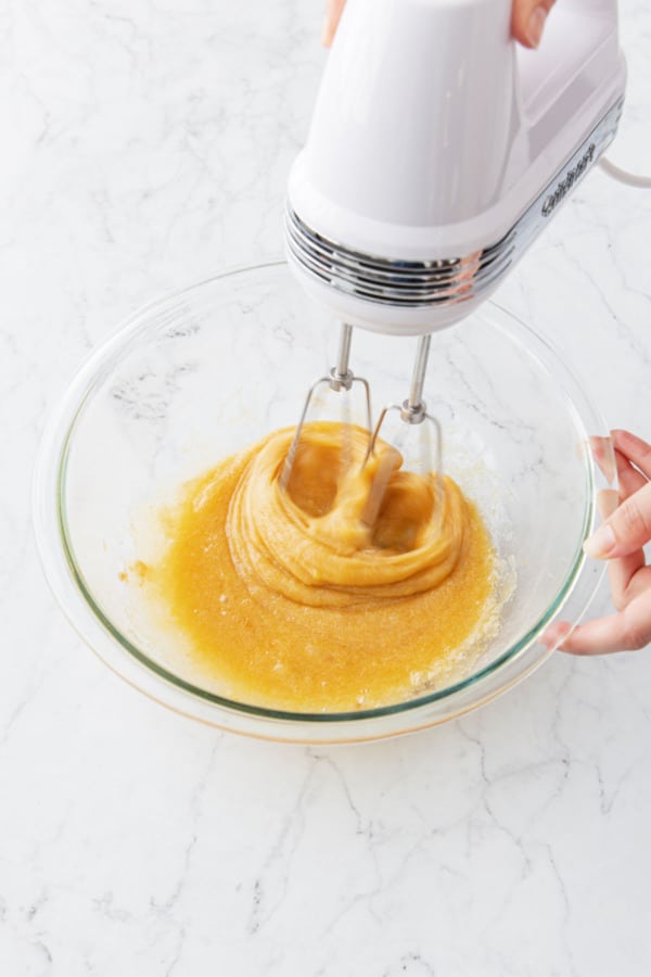 Beating the eggs and sugar together with an electric mixer.