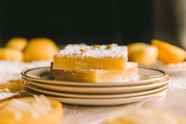 eye level view of two lemon bars recipe on a stack of vintage plates