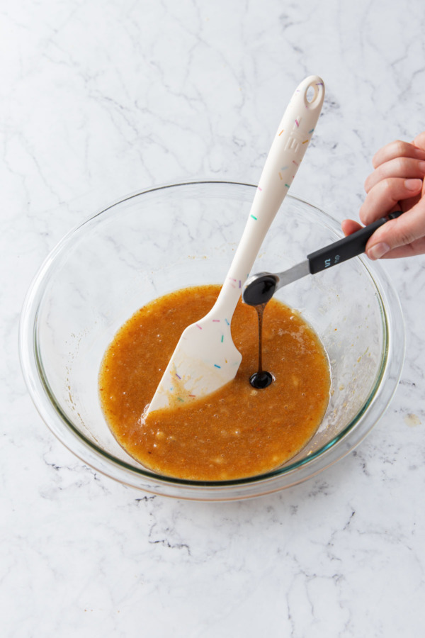Measuring 1/2 teaspoon vanilla bean paste into cookie batter.
