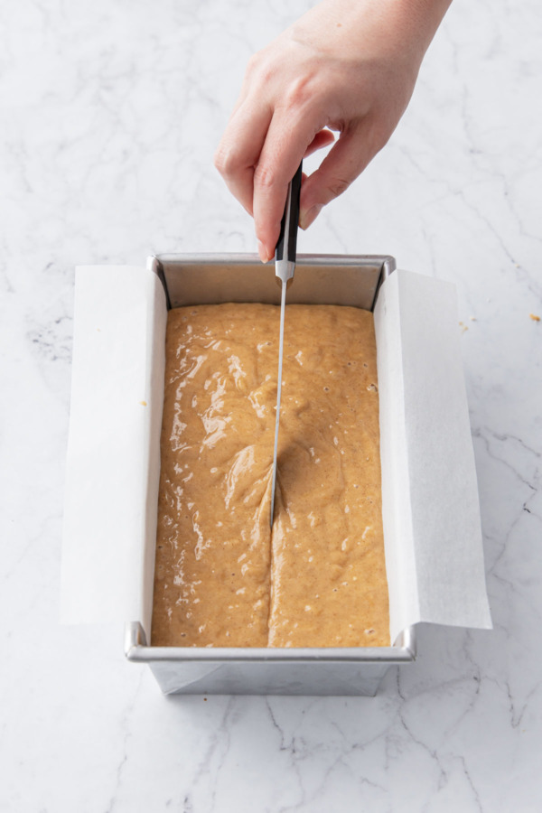 Running a buttered knife down the middle of the raw batter before baking.