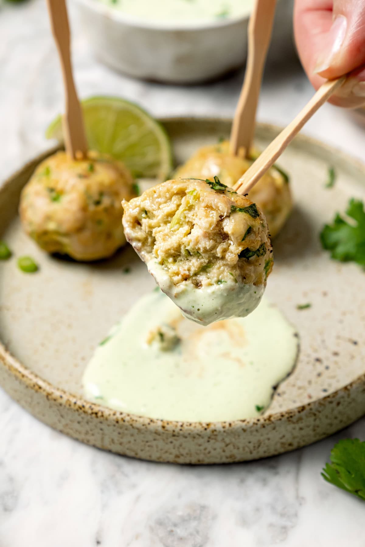 Dipping baked turkey meatball into creamy sauce.