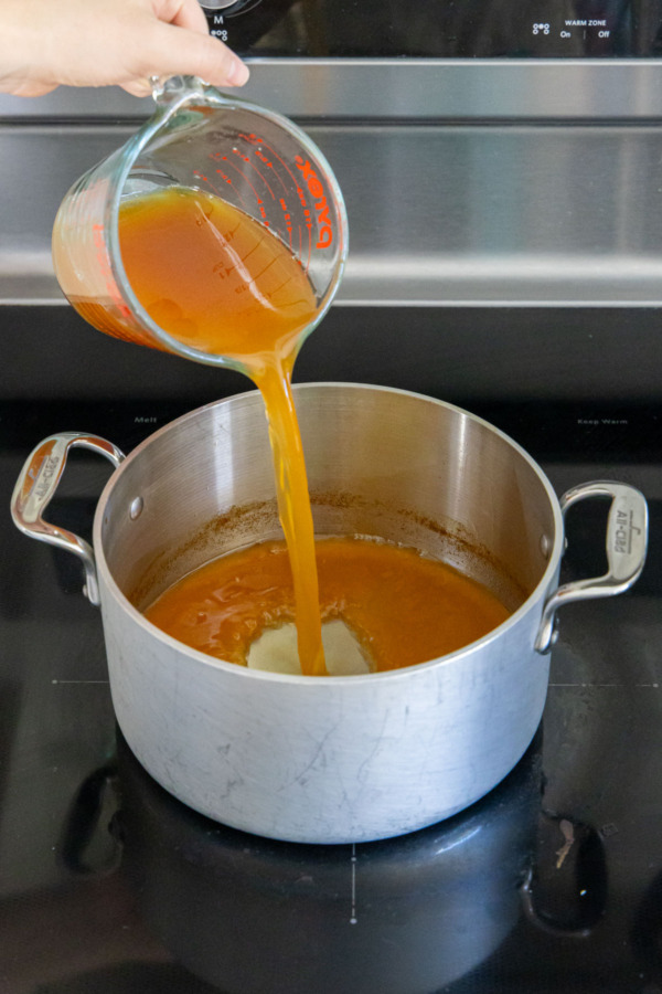 Pouring apple cider back into saucepan.