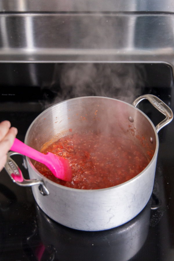 Stirring until sugar and pectin are fully dissolved into boiling pepper jelly mixture.